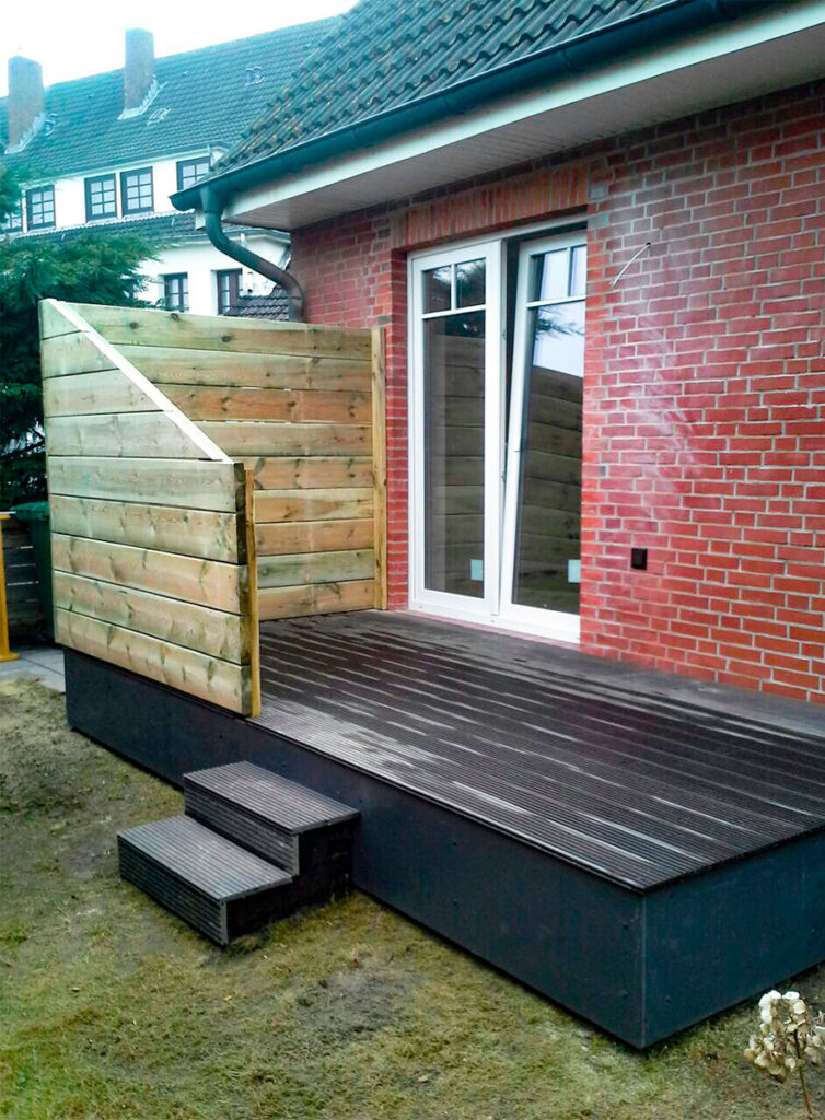 Nachher-Ansicht einer erhöhten Holzterrasse mit Wind- und Sichtschutz.