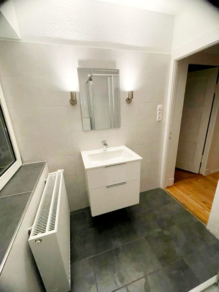 Nachher-Ansicht einer Badsanierung mit modernen Fliesen und Armaturen.